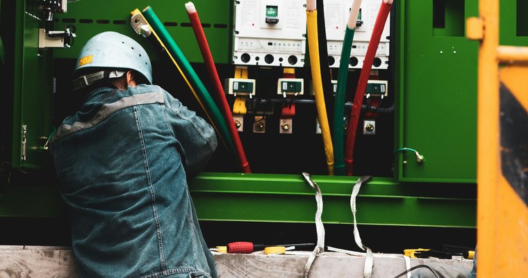 Technicien en intervention sur une armoire électrique avec câbles de phase de section importante