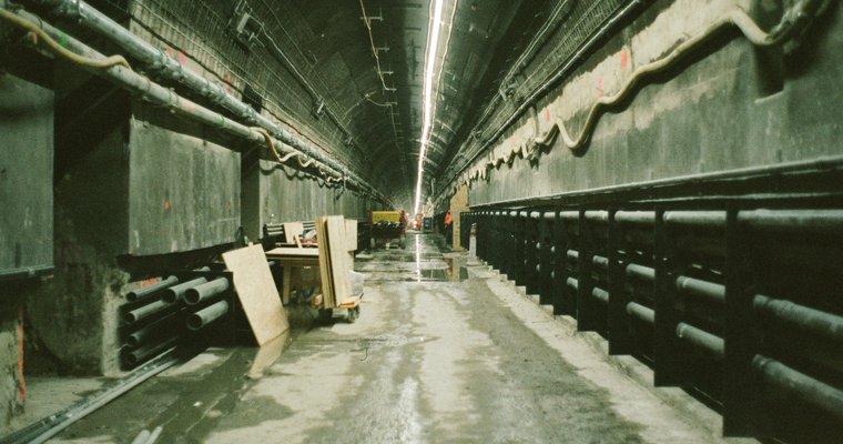 Galerie technique souterraine avec câbles électriques posés sur étagères, ambiance maintenance préventive
